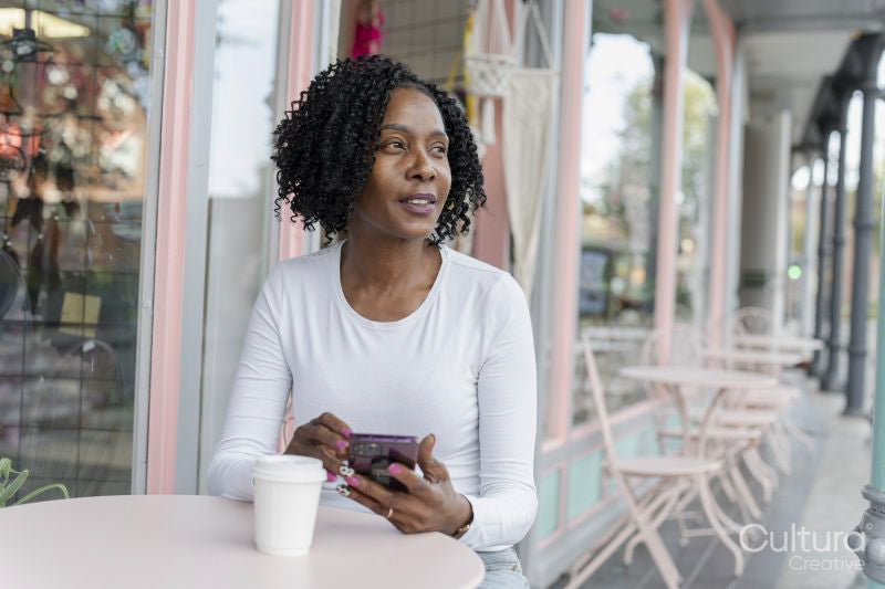 Woman using smart phone during coffee break in sidewalk cafe