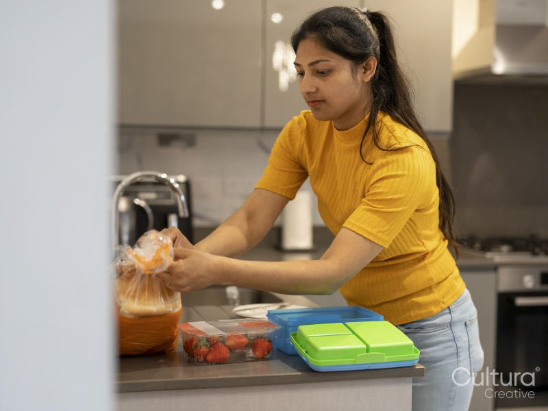 Young woman preparing lunch boxes in kitchen