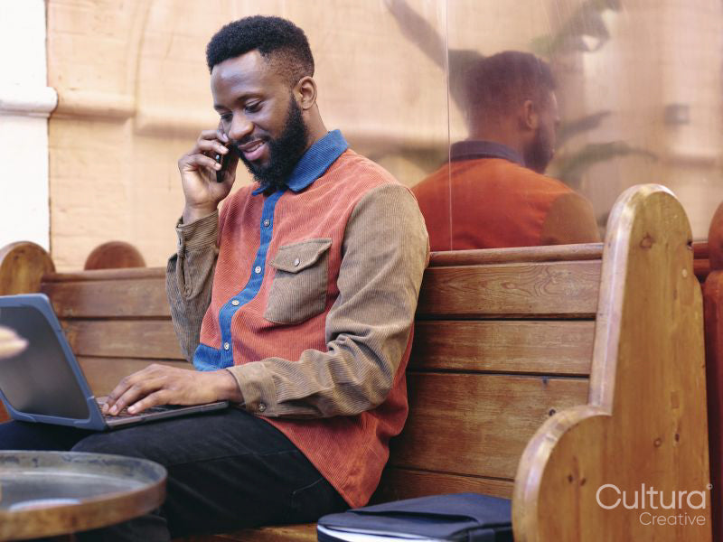 Smiling businessman using smart phone and laptop