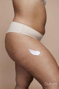 Studio shot of young woman using anti-cellulite cream