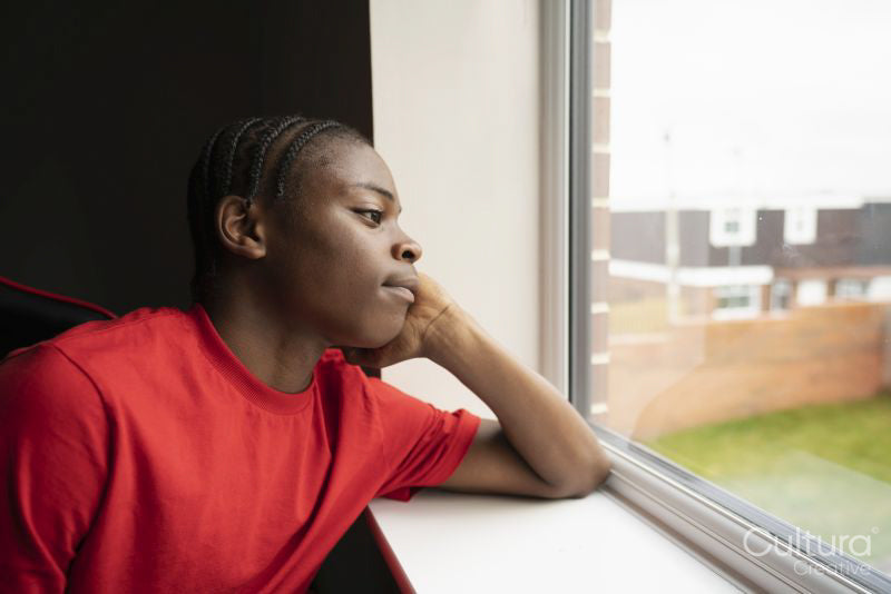 Teenage boy looking through window at home