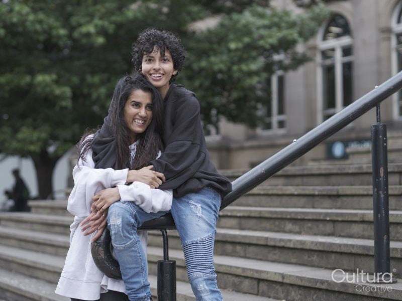 Female couple hugging on stairs in city