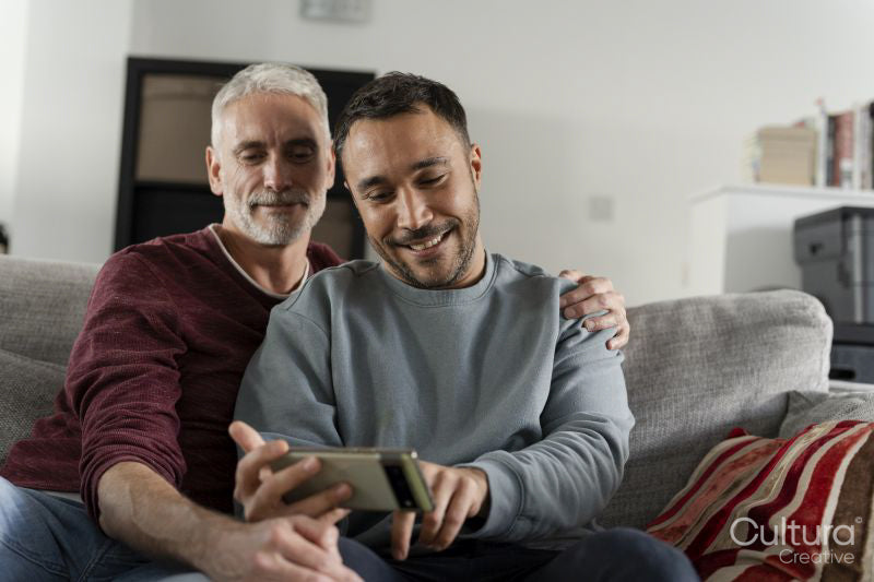 Smiling male couple taking selfie on sofa