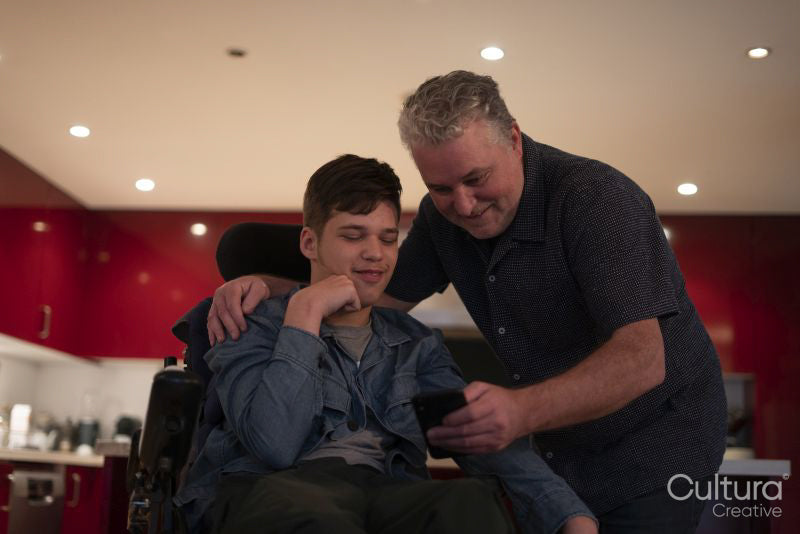 Father using smartphone with disabled son at home
