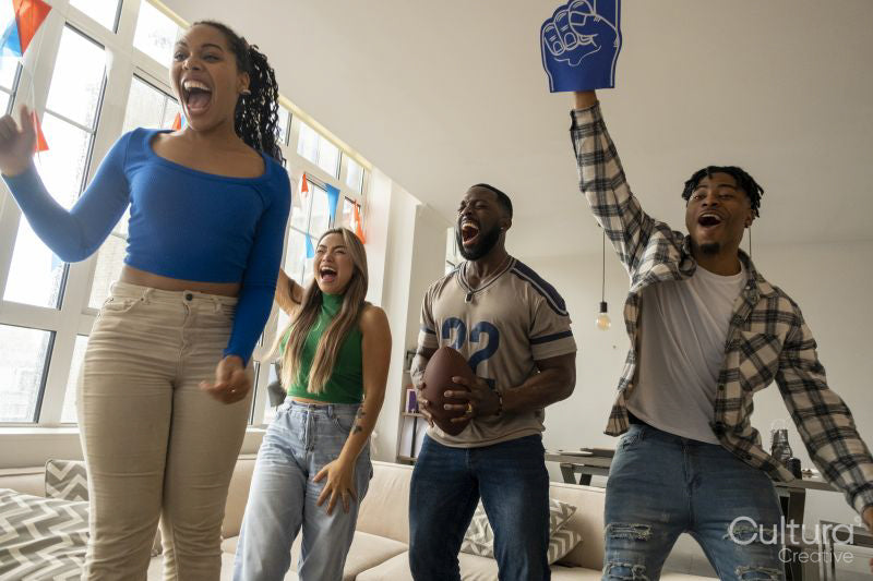 Excited friends watching sport game on TV at home