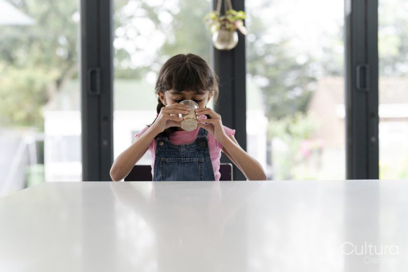 Little girl drinking from mug at table