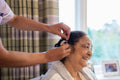 Nurse helps senior lady putting on hearing aid at nursing home