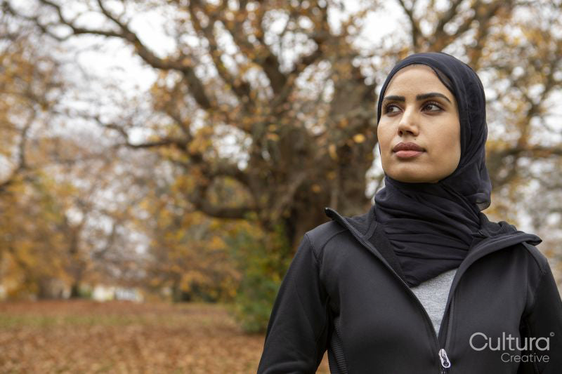 Portrait of woman in black sports clothing and hijab in park