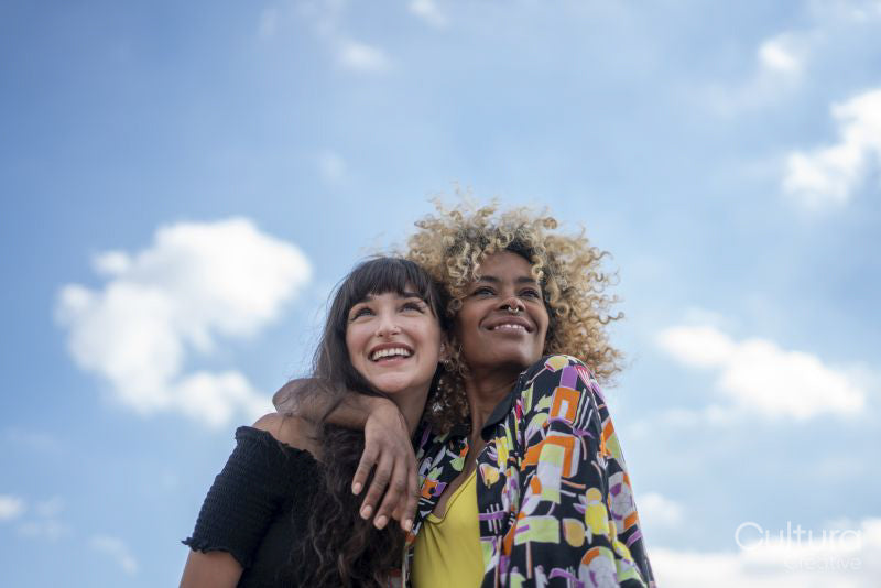 Female couple embracing against blue sky