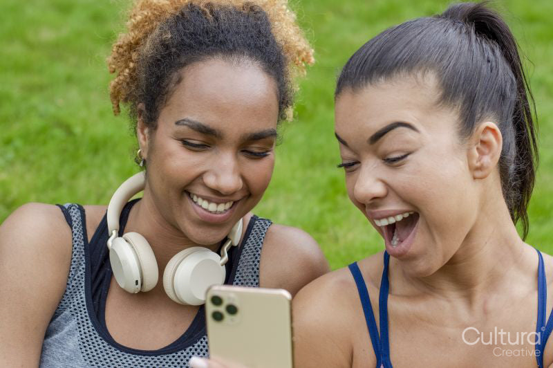 Two women laughing while sharing smart phone