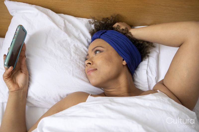 Woman looking at smart phone in bed