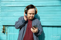 Mid adult man wearing headphones, holding smartphone
