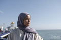 Portrait of thoughtful Muslim woman looking at sea on sunny day