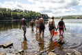 Rear view of group of friends entering lake, Yorkshire, UK