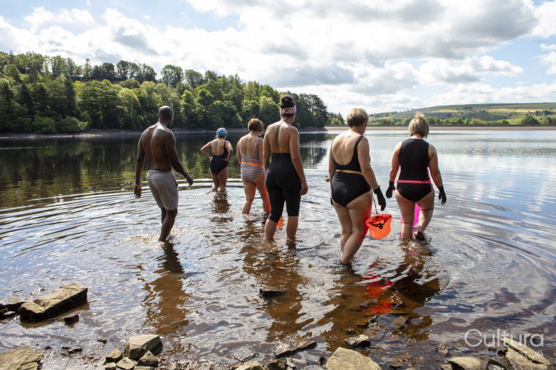 Rear view of group of friends entering lake, Yorkshire, UK