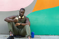 Mid adult man sitting on sidewalk and using phone