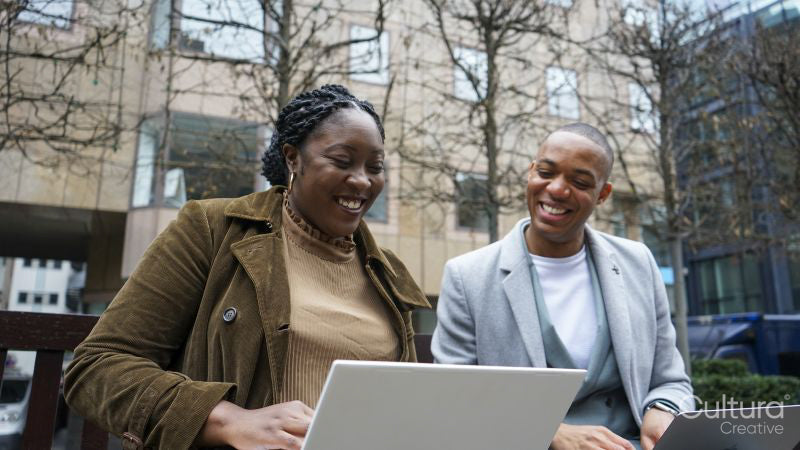 Business man and woman sitting on bench using laptop