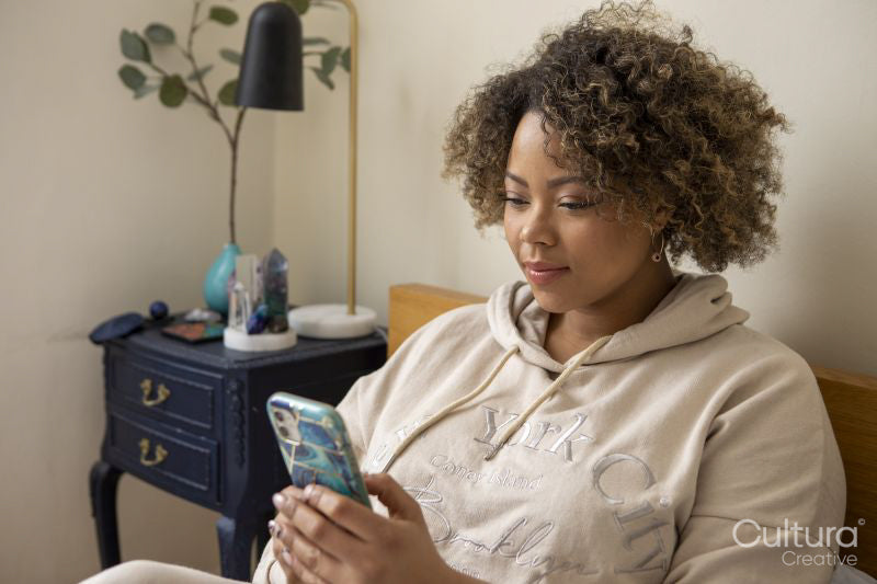 Woman sitting on bed and looking at smart phone