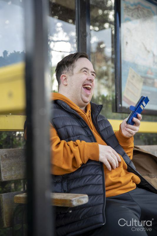Man sitting on bench at bus stop, using smart phone