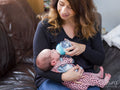 Mother bottle feeding infant daughter
