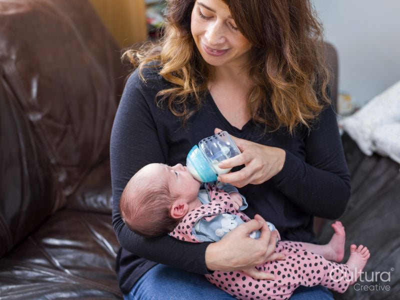 Mother bottle feeding infant daughter