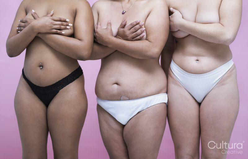 Studio shot of three shirtless women covering breasts