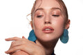 Studio portrait of a woman in a blue dress and large blue earrings