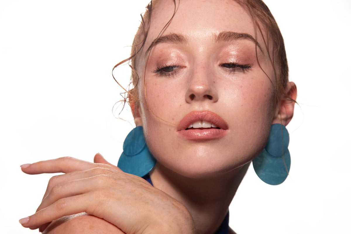 Studio portrait of a woman in a blue dress and large blue earrings