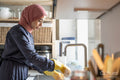 Mid adult woman in hijab washing dishes at home