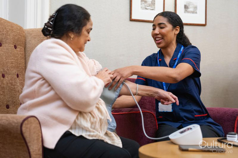 Nurse taking blood pressure of senior woman at nursing home