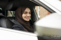 Young woman wearing hijab driving car