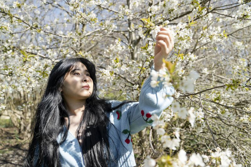 Young woman touching tree blossom