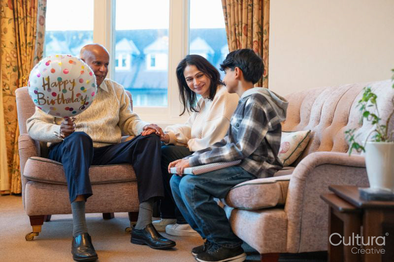 Mature woman and boy visiting senior man for birthday in nursing home