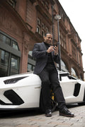 Mature man leaning against luxury car and using phone