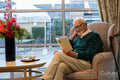 Smiling senior man sitting in armchair and reading book