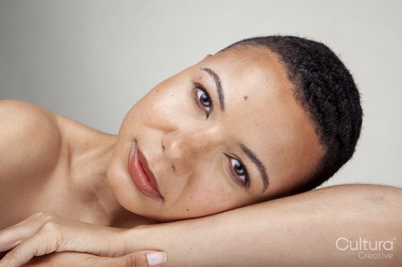 Studio portrait of shirtless woman leaning on arm