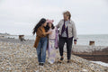 Grandmother, mother and daughter walking on beach on cloudy day