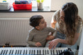 Mother and son playing music keyboard at home