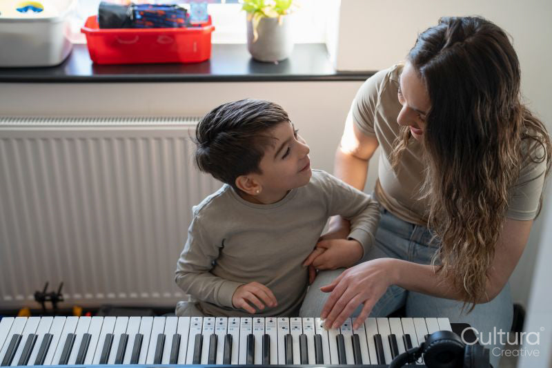 Mother and son playing music keyboard at home