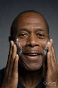 Portrait of man applying cream on face