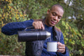 Man pouring warm drink during hike in autumn