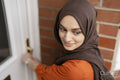 Woman in hijab locking house door