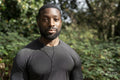 Portrait of athletic man with earbuds standing in park