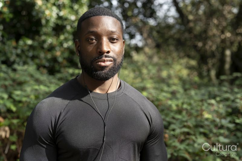 Portrait of athletic man with earbuds standing in park