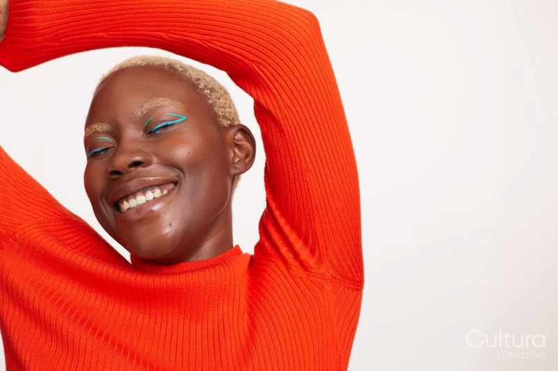 Portrait of smiling woman with short white hair, raising arms