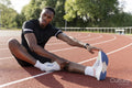 Athlete stretching legs before training at sports track