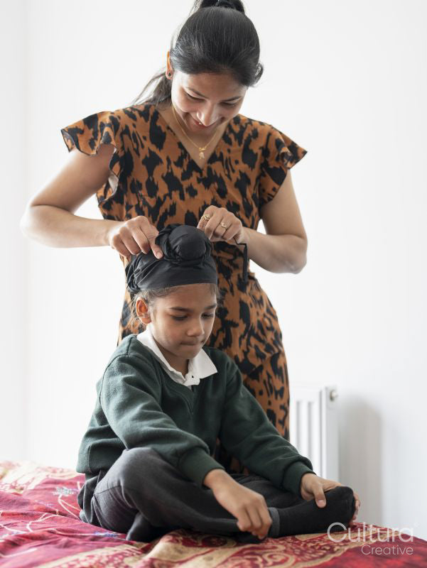Mother wrapping traditional turban on son's head