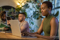 Woman sitting at table with friends and using laptop