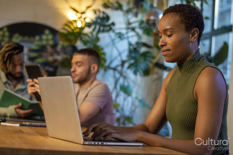 Woman sitting at table with friends and using laptop