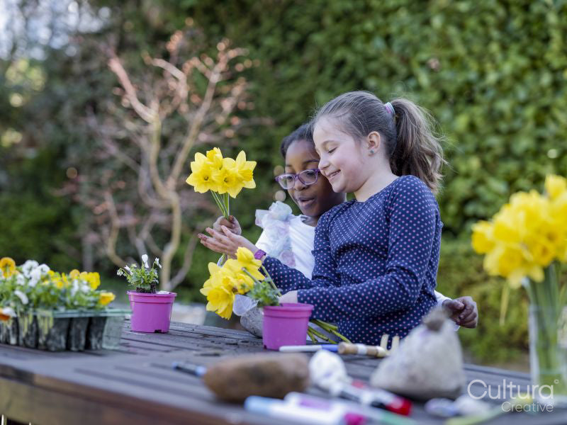 Girl friends potting plants in back yard